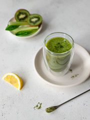 a glass of green smoothie with spinach, celery, kiwi, lemon and spirulina. Superfoods and health food concept. Gray background. top view, vertical image. selective focus.