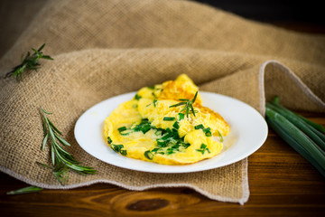hot fried omelet with chopped green onions in a plate - obrazy, fototapety, plakaty
