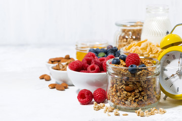 healthy products for breakfast, granola and berries on white table