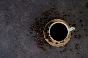 Obraz na płótnie Canvas Cup of black coffee with coffee beans around, top view