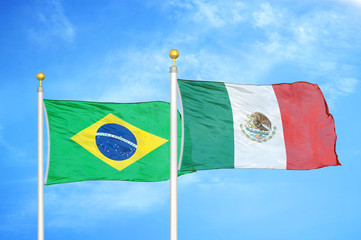 Brazil and Mexico two flags on flagpoles and blue cloudy sky