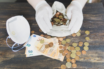 Financial crisis in the world. Hands in protection gloves, mask, money on table. World economy hit by coronavirus Covid-19 outbreak and pandemic fears. Crisis, bank, saving and finance concept. 