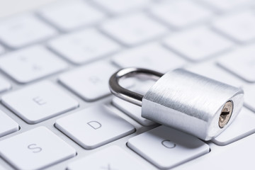 Data safety. Steel lock laying on a white minimalistic keyboard