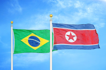Brazil and North Korea two flags on flagpoles and blue cloudy sky
