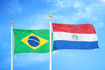 Brazil and Paraguay two flags on flagpoles and blue cloudy sky