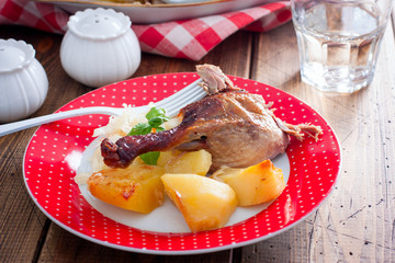 Chicken leg with potatoes on a plate on a wooden table, selective focus