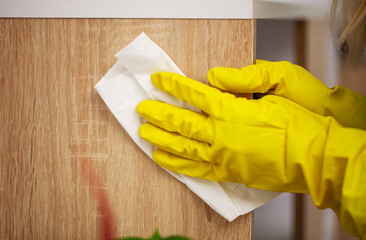 Close up of worker hand wiping dust in office in yellow gloves