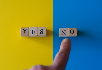 Yes or no. Finger pointing the word no. Blue and yellow background.