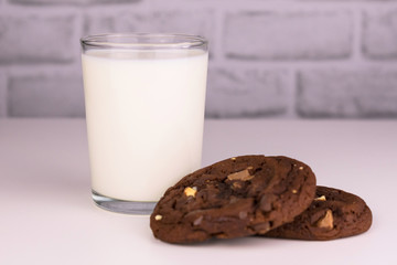  Milk in a glass and chocolate homemade cookies on a white background. Concept for a delicious snack.