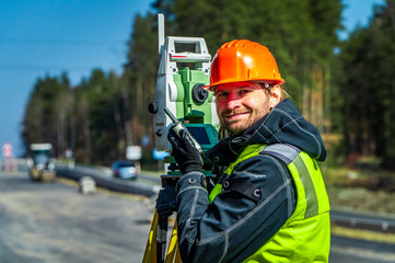 Surveyor engineer with equipment (theodolite or total positioning station) on the construction site...