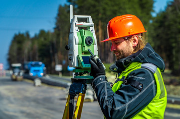 Surveyor engineer with equipment (theodolite or total positioning station) on the construction site...