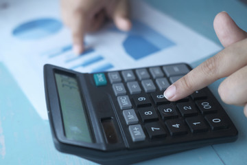 Close up of women using calculator at office desk.
