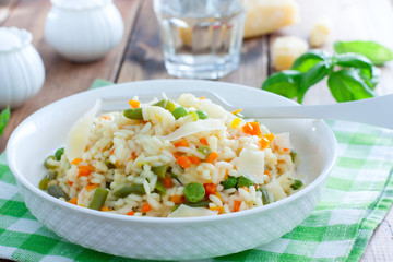 Italian risotto with vegetables - peas, beans, carrots, peppers on a white plate, selective focus
