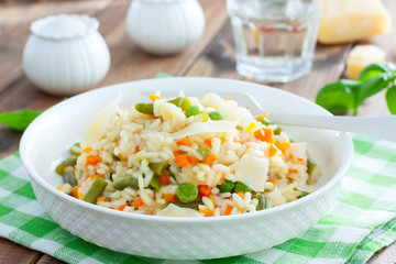 Italian risotto with vegetables - peas, beans, carrots, peppers on a white plate, selective focus