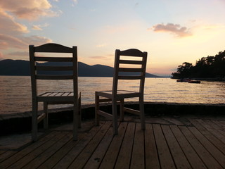 Fototapeta na wymiar the two empty chair at the sunset between the coast