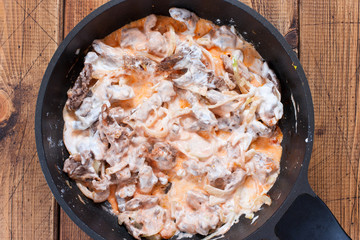 Step-by-step preparation of beef stroganoff, step 5 - adding sour cream and tomatoes, top view,...