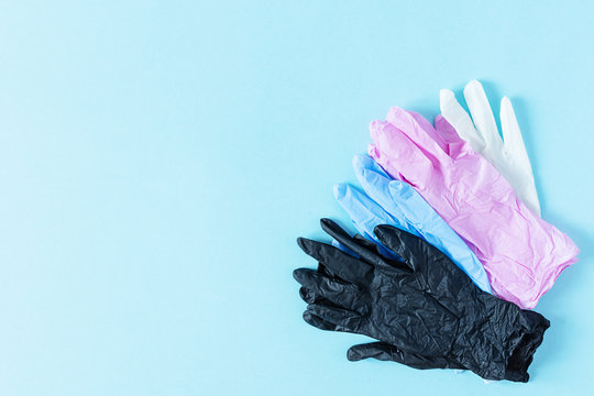 Pile Of Multi Colored Latex Surgical Gloves For Protection On Blue Background.