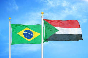 Brazil and Sudan two flags on flagpoles and blue cloudy sky