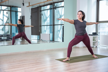 Fototapeta na wymiar Photo of young woman practicing yoga indoor. Beautiful girl practice yoga in class. Yoga studio instructor. Blurred background.