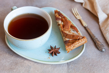 Apple pie, cup of fragrant tea, anise and cutting knife in rustic style on a wooden background