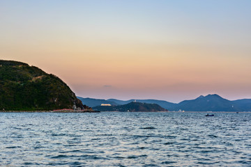 Sunset, sand, clear turquoise sea, coral reefs on the coast of Xiaodonghai Bay in South China Sea. Sanya, island Hainan, China.