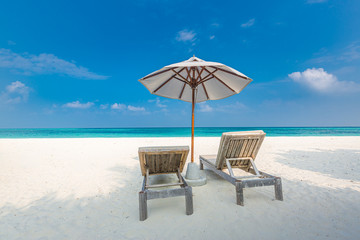 Island beach with loungers and umbrella on white sand close to blue sea. Idyllic summer travel and vacation landscape