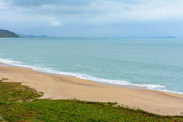 Fototapeta na wymiar Cloudy day, sand deserted beach of the coast in South China Sea. Sanya, island Hainan, China. Nature Landscape.