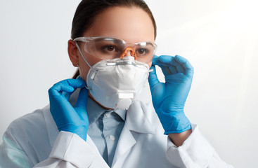 portrait of a woman doctor in protective gloves, glasses and a respiratory mask.