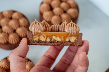 Hand holds a half of tart with caramel and nuts