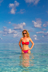 Beautiful young woman in sexy bikini standing at sea beach enjoying summer weather, sunny day, blonde woman, bikini, sunglasses