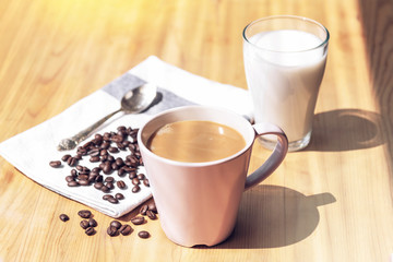 Cup of coffee and glass of almond milk on wooden table, close up.