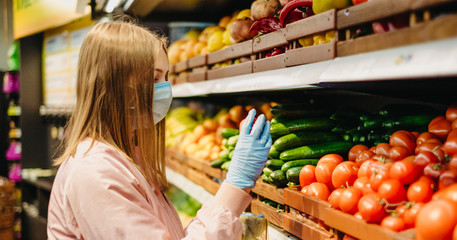Young girl in medical masks makes purchases in a supermarket in search of food.