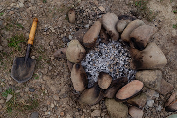 campfire ash stones around sapper shovel