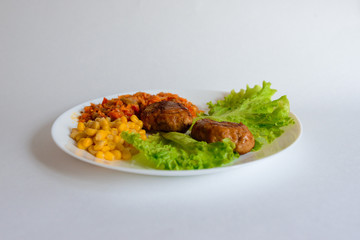 Fried chicken cutlet with potato slices served with tomato cherry and corn salad. Traditional belorussian food - roasted minced meat and potato