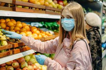 Young girl in medical masks makes purchases in a supermarket in search of food.