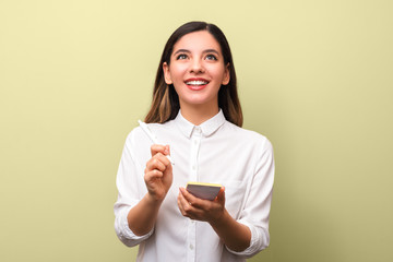 closeup young cheerful businesswoman with beautiful healthy smile holding pen making notes and looking up against yellow background