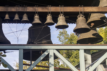 Small bells with patterns, suspended in a row in ascending order in size and connected by a grid of ropes against the background of large bells