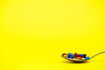 Spoon full of pills for weight loss on yellow background.