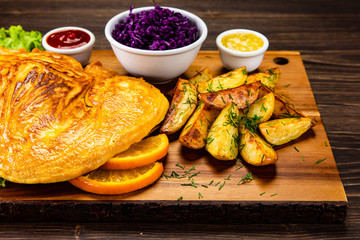 Schnitzel with baked potatoes on wooden background