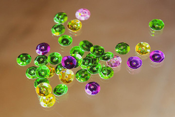 A pile of round colored sequins on the glass. Material for needlework