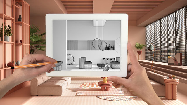 Hands holding and drawing on tablet showing colored contemporary living room CAD sketch. Real finished interior in the background, architecture design presentation