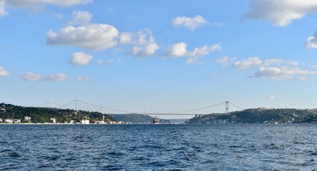 Fototapeta na wymiar Commercial vessel is passing under Istanbul Bosporus Bridge in a nice summer day