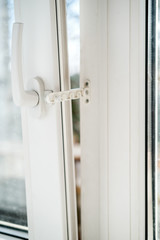 Open white PVC window with a fixing device for ventilation, in natural light. Horizontal photo.