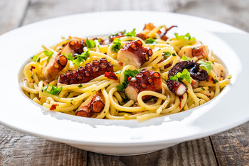 Spaghetti with fried octopus on wooden table