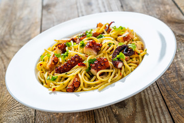 Spaghetti with fried octopus on wooden table