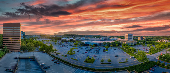 Aerial sunset view of Columbia town center in Howard Country Maryland with dramatic red, orange, blue, purple colors over the office and residential buildings - obrazy, fototapety, plakaty