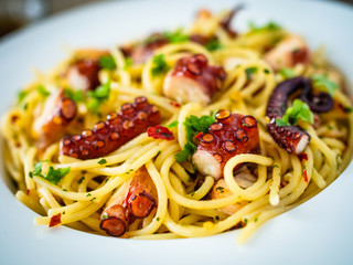 Spaghetti with fried octopus on wooden table