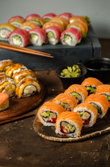 Set of traditional japanese food on a dark background. Sushi rolls, nigiri, raw salmon steak, rice, cream cheese, avocado, lime, pickled ginger. Asian food frame. Dinner party.