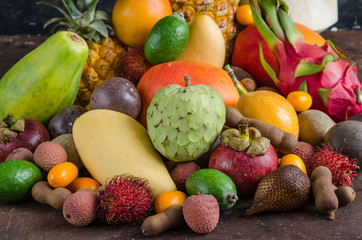 Healthy eating, varieity of tropical fruits on a dark background. Metal baskets with pineapple, mango, granadilla, passion fruit, mangosteen and kumquat.