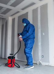 a man in a special suit paints walls with a spray gun, painting walls and ceilings